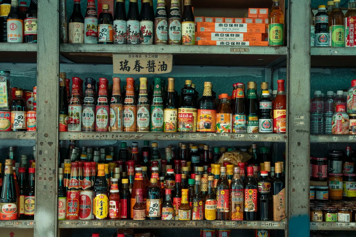 Bouteilles et pots d'ingrédients asiatiques alignés : sauce soja, huile de sésame, vinaigre de riz, nuoc-mâm et pâte de gochujang