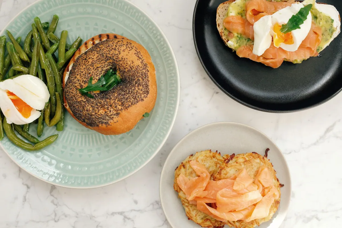 Bagel toasté garni d'avocat écrasé et de tranches de saumon fumé