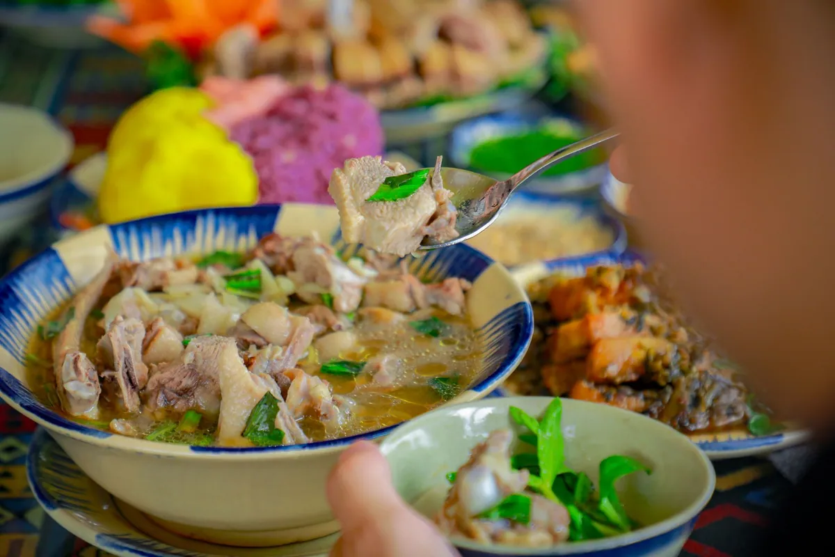 Bol de canh chua cá, soupe aigre-douce vietnamienne au poisson, ananas, tomate et gombo, garnie d'herbes fraîches et de piment, servie avec du riz blanc.