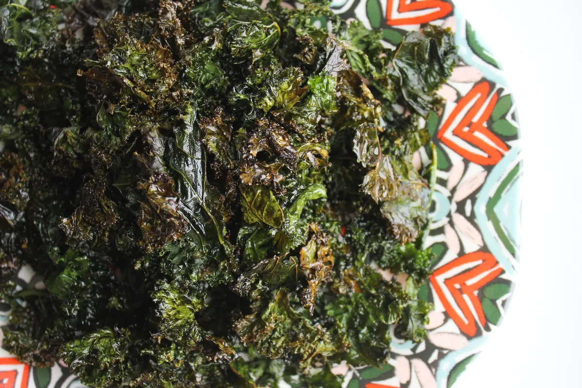 Chips de kale croustillantes étalées sur une plaque de four