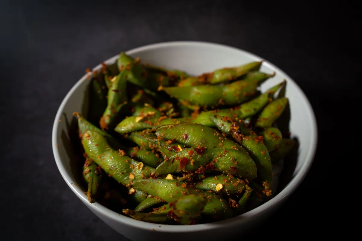 Edamame épicés dans leur cosse saupoudrés de sel et de piment dans un bol