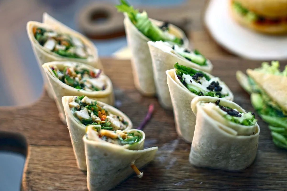 Roulés de tortilla au houmous coupés en tronçons, révélant les légumes croquants
