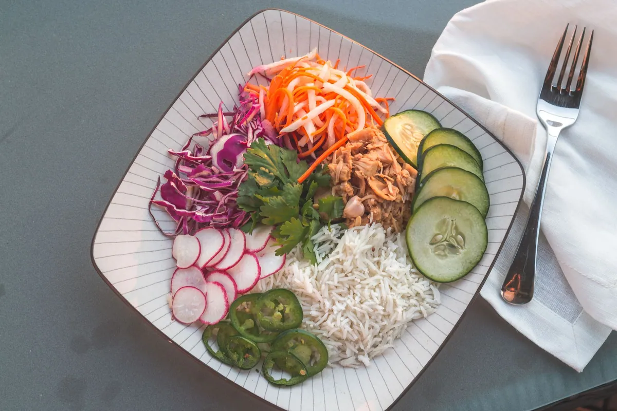Salade de riz froide avec thon émietté, concombre, radis et maïs dans un bol